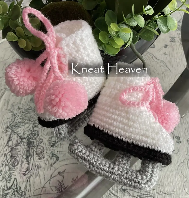 White crochet baby ice skate booties with grey blades and pink pom-poms